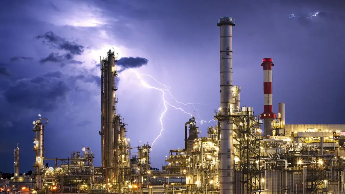 Planta industrial iluminada durante tempestade noturna