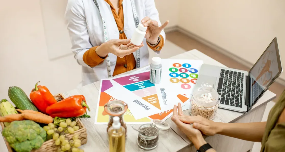 Nutricionista organizando alimentos e anotações ao lado de notebook
